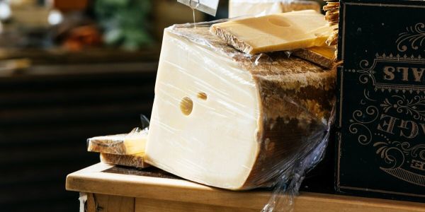 Large wheels and slices of artisan cheese displayed on a wooden counter at a Vermont market