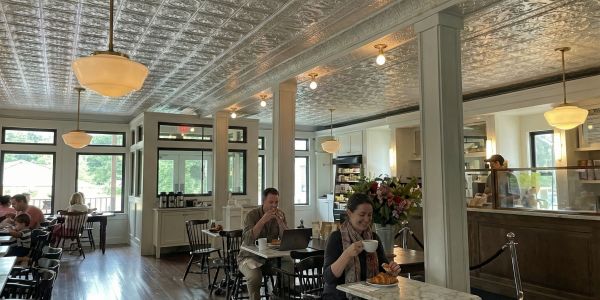 Assorted glass bottles of Vermont maple syrup arranged on a wooden shelf at a local market
