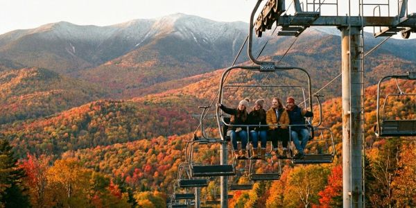 Couple in ski gear sitting on a wooden bench in the snow, sharing a warm drink during a winter day in the mountains