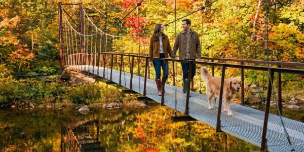 People riding a chairlift over colorful fall foliage with mountain views in the Catskills.