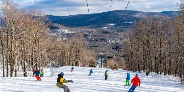 Group of friends standing in the snow with colorful snow tubes at a winter resort in the Catskills.