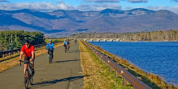 Couple in ski gear sitting on a wooden bench in the snow, sharing a warm drink during a winter day in the mountains