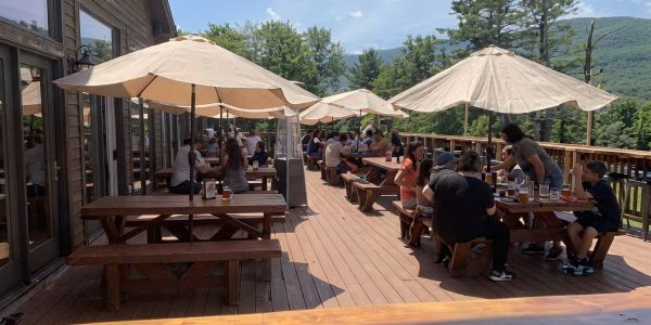 Large wheels and slices of artisan cheese displayed on a wooden counter at a Vermont market