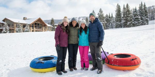 Group of friends standing in the snow with colorful snow tubes at a winter resort in the Catskills.