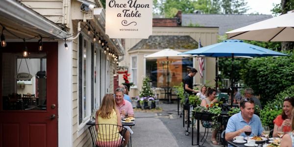 People enjoying outdoor dining at a cozy village restaurant in the Berkshires during a warm summer evening.