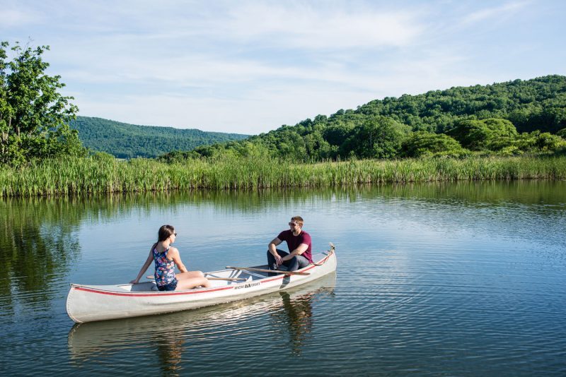 2 people in a canoe with mountains in the back 