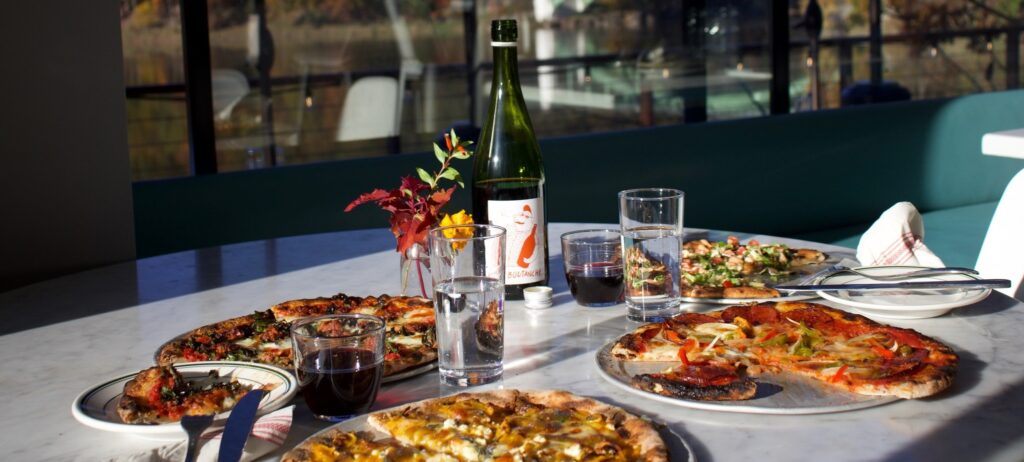 A few pizza pies with some wine