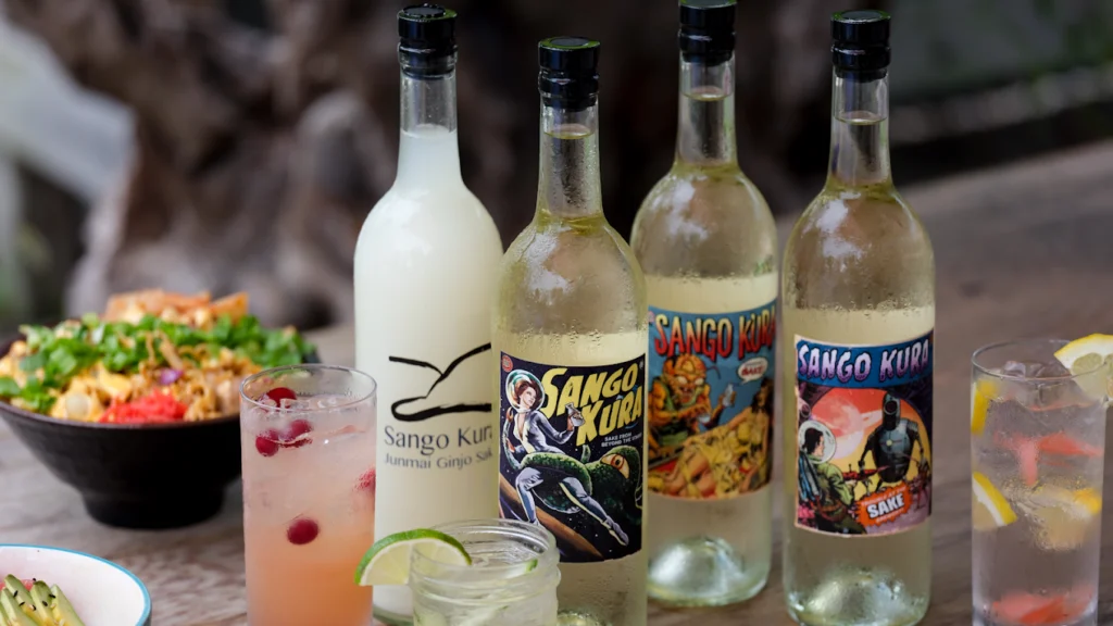 Bottles of house made sake and some food in the background